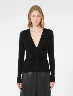 Model wearing a black deep-V ruched long-sleeve top and dark wide-leg leather pants, facing forward.
