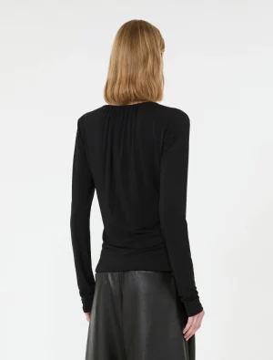 Back view of a person wearing a black long-sleeve top tucked into a black faux leather skirt, blonde hair.