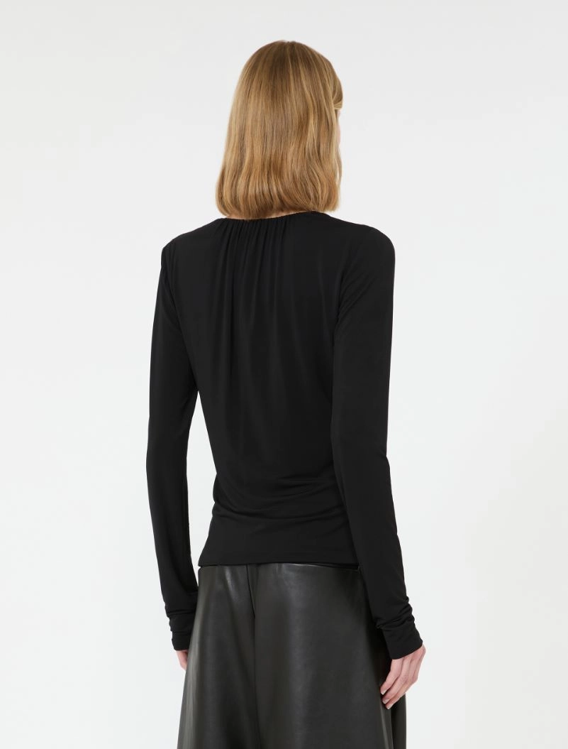IMG_3073 - New Trend Back view of a person wearing a black long-sleeve top tucked into a black faux leather skirt, blonde hair.