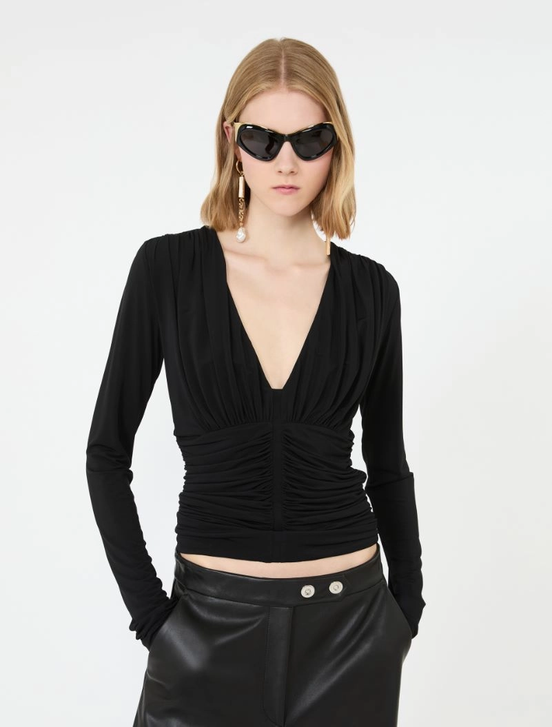IMG_3074 - New Trend Model wearing a black ruched V-neck top with black leather pants, accessorized with oversized sunglasses and dangling earrings.