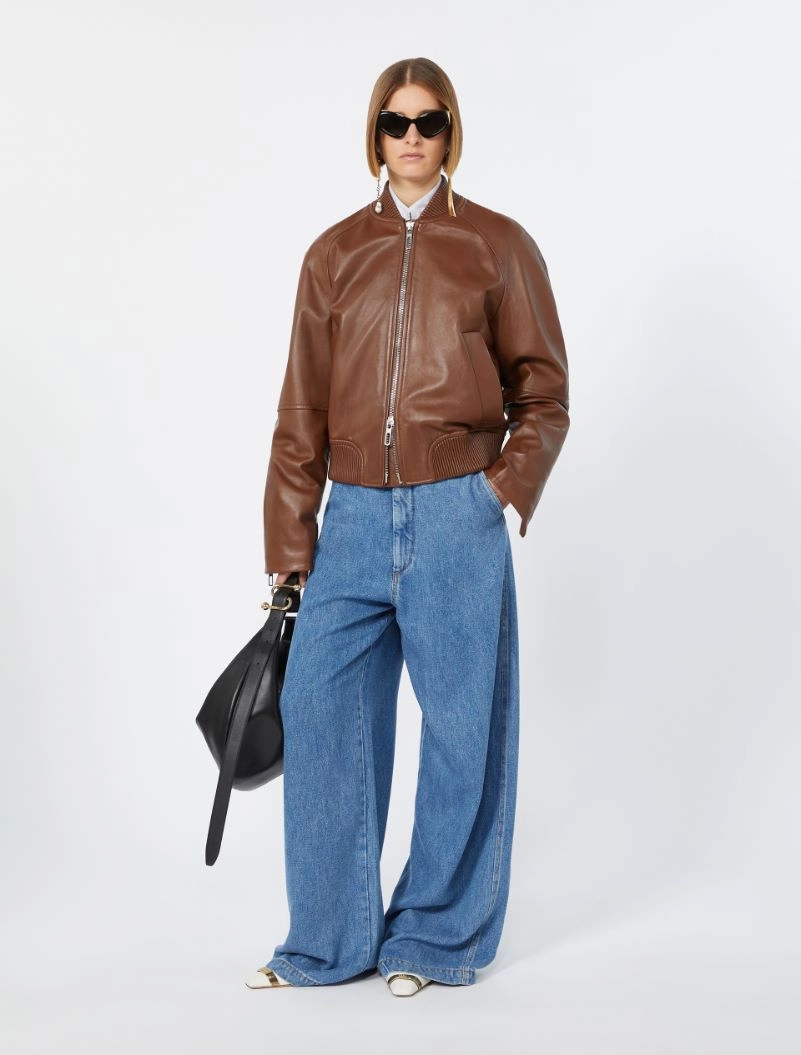 IMG_3077 - New Trend Model wearing a brown leather bomber jacket with wide-leg blue jeans, white shirt, black sunglasses, and a black handbag.