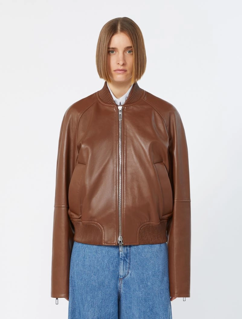 IMG_3078 - New Trend Model wearing a brown leather bomber jacket with a front zipper, ribbed collar, cuffs, and hem, paired with blue jeans (front view).