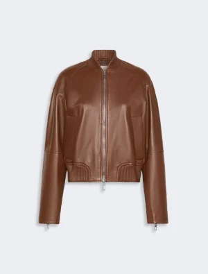 Brown leather bomber jacket with front zipper and ribbed cuffs on a light gray background.
