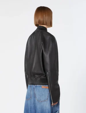 Back view of a person wearing a black leather bomber jacket with ribbed collar and waistband, paired with blue jeans.