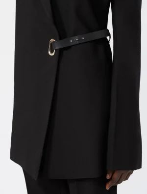 Close-up of a black coat's waist with a slim black belt and a gold buckle cinching the garment.