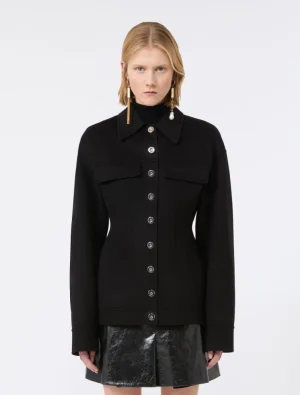 Model wearing a black button-up jacket with wide collar and front flap pockets, paired with a shiny black mini skirt.