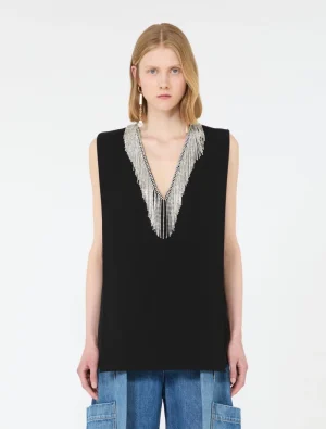 Model wearing a sleeveless black top with a silver beaded V-shaped neckline detail, paired with blue denim cargo jeans in a studio setting.