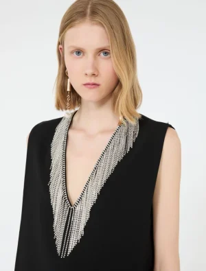 Model wearing a black sleeveless top with a long silver beaded fringe necklace.