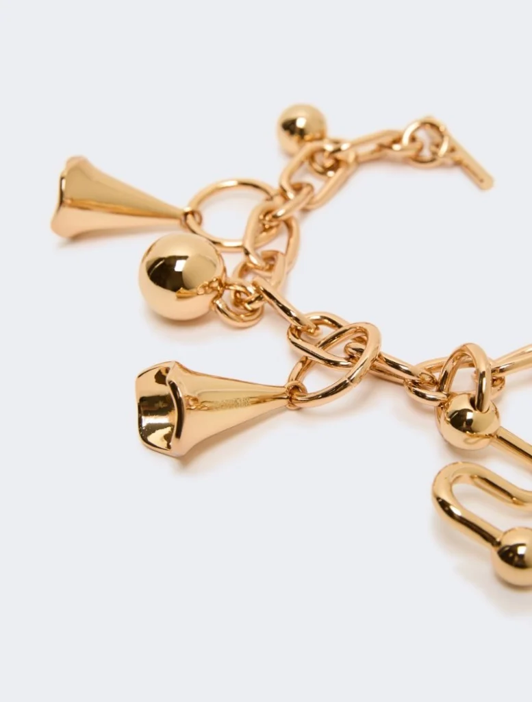 Close-up of a gold charm bracelet with bell-shaped charms and round beads on a delicate chain