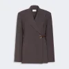 Brown belted, wrap-style blazer with wide lapels and a neutral background for a tailored look.