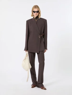 Model wearing a dark brown oversized blazer with a matching belt, wide-leg trousers, brown loafers, sunglasses, and a cream bag.