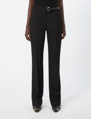 Black high-waisted wide-leg trousers with a slim belt on a model, paired with black shoes with gold accents.