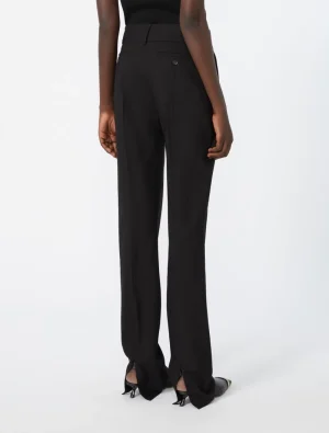 Back view of a person wearing black tailored wide-leg pants with a high waist, belt loops, and back pocket, paired with black heeled shoes.