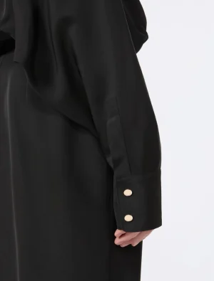 Close-up of a black coat sleeve with a double-button cuff and gold buttons.