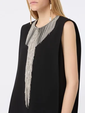 Close-up of a black sleeveless dress accented by a dramatic silver beaded fringe necklace draping down the front.