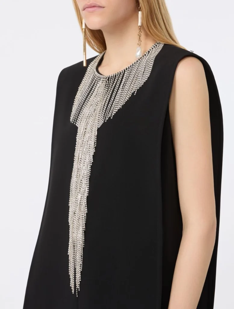 Close-up of a black sleeveless dress accented by a dramatic silver beaded fringe necklace draping down the front.