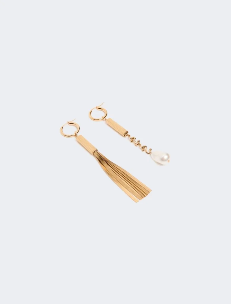 Gold-tone hoop earrings with a tassel on one and a pearl drop on the other on a white background