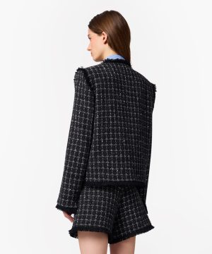Back view of a black-and-white tweed blazer with fringe trim and matching shorts.