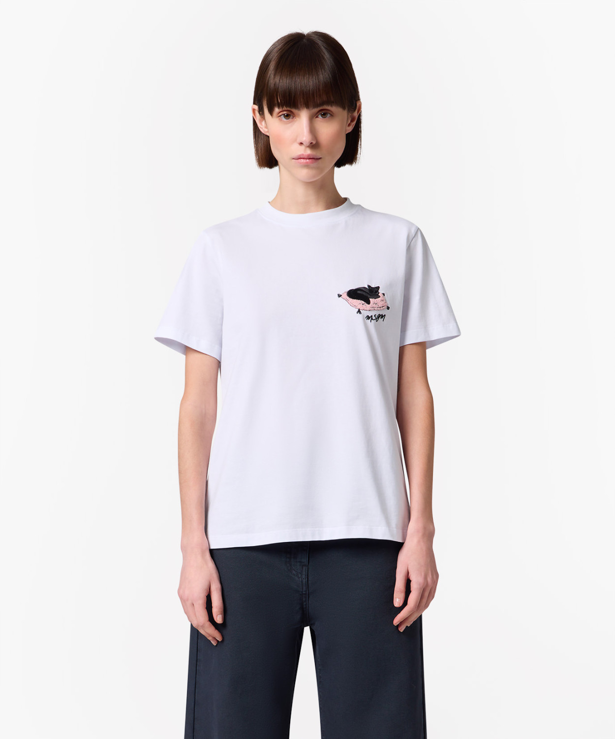 IMG_3201 - New Trend Model wearing a white T-shirt with a small embroidered patch on the left chest, paired with dark navy pants.