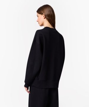 Back view of a person wearing an oversized black sweatshirt against a white background.