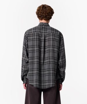 Back view of a person wearing a gray plaid flannel shirt, standing against a white background.