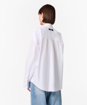Back view of a person in a white long-sleeve button-down shirt and light-wash jeans, brown bob haircut, small label on the upper back.