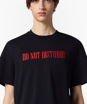 Person wearing a black T-shirt with red embroidered text reading 'DO NOT DISTURB!' on the chest area