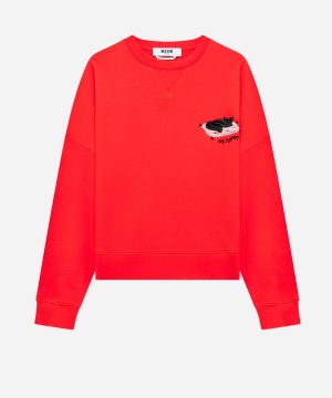 Bright red crewneck sweatshirt with a small embroidered black cat on a white cushion patch on the chest, and a visible label at the neckline.