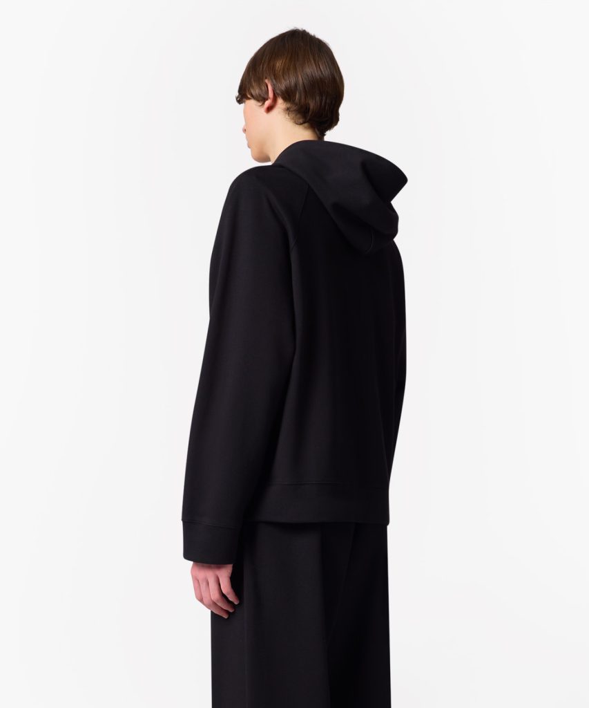 Person wearing a black hoodie, shown from the back against a white background.