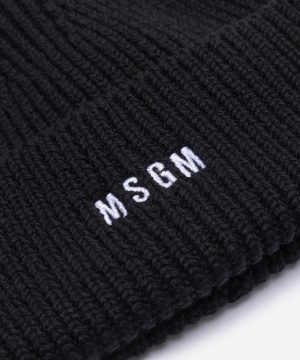 Close-up of a black knit fabric with white embroidered letters reading WSCM.