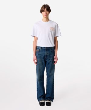 Model wearing a white short-sleeve T-shirt with loose blue jeans, standing against a plain light background.