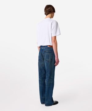 Person standing with back to camera, wearing a white T-shirt and high-waisted blue jeans.