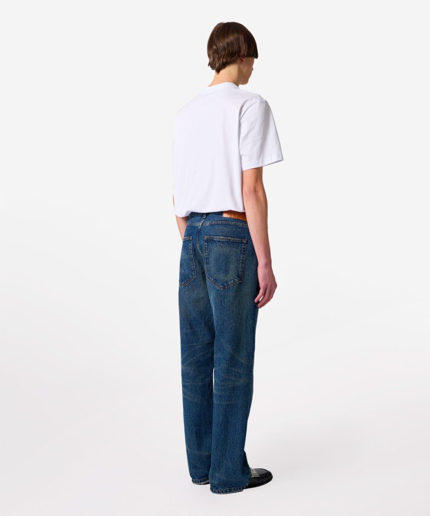 Person standing with back to camera, wearing a white T-shirt and high-waisted blue jeans.