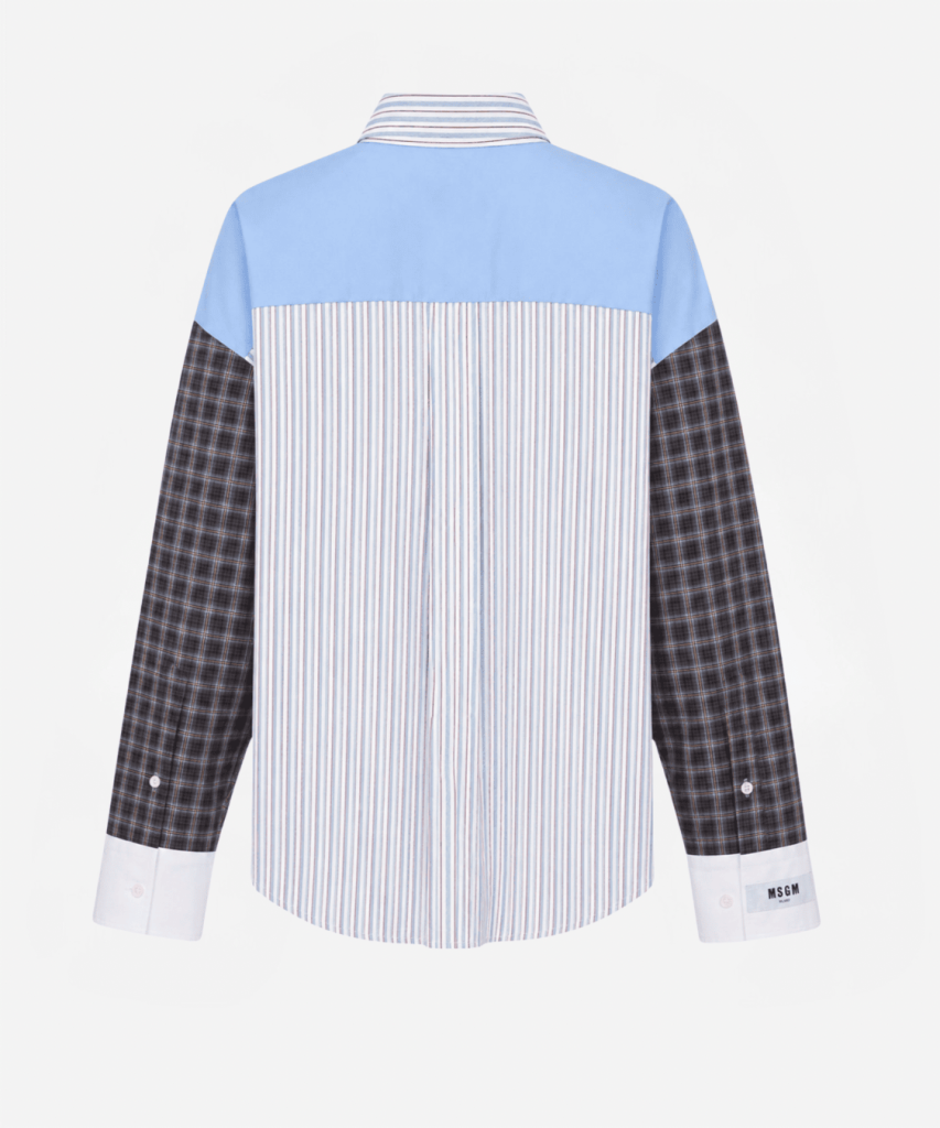 Back view of a color-block shirt: light blue yoke, vertical blue-and-white striped center panel, and dark plaid sleeves with white cuffs.