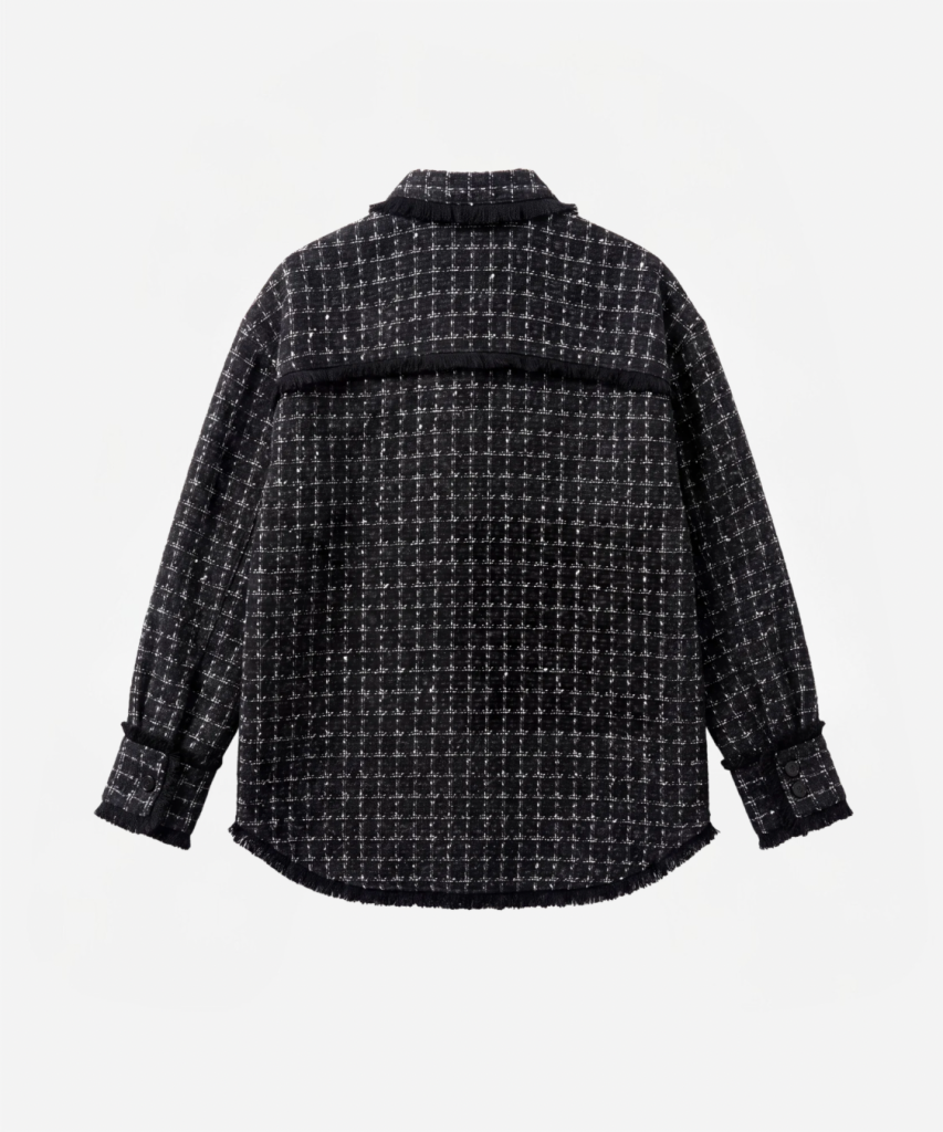 Back view of a black-and-white checkered tweed jacket with fringe trim along the yoke and hem, long sleeves with buttoned cuffs.