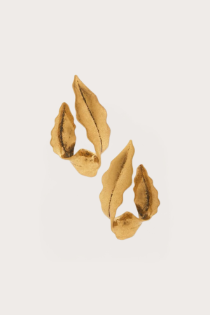 Gold-painted dried leaves scattered along the bottom of a pale background, forming a delicate cluster