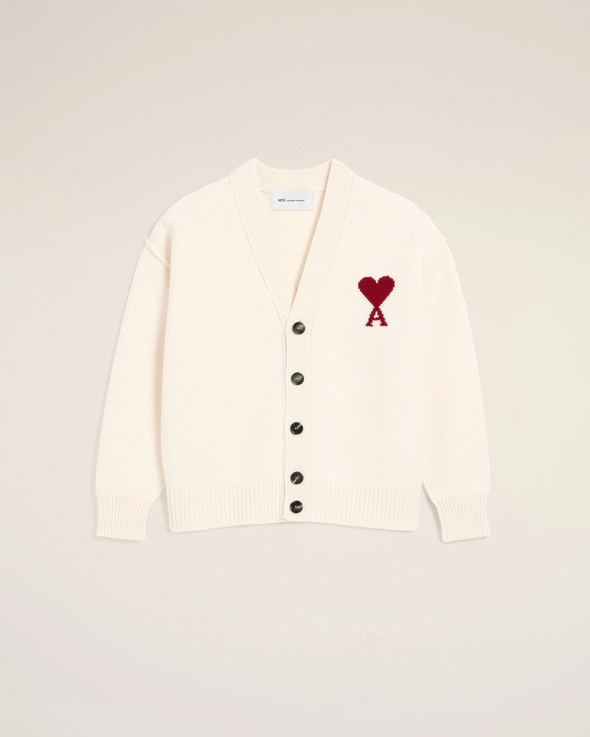 IMG_3432 - New Trend Cream cardigan with a red heart appliqué on the left chest, button-front and ribbed cuffs against a pale beige background.