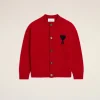 Red cardigan with a black heart patch on the left chest, button-front, shown against a light beige background.