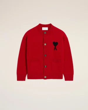 Red cardigan with a black heart patch on the left chest, button-front, shown against a light beige background.