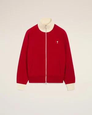 Red zip-front jacket with a cream ribbed collar and cuffs, featuring a small white heart emblem on the left chest.