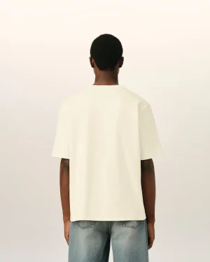 Back view of a person wearing a cream T-shirt and blue jeans against a pale neutral background.