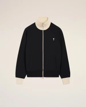 Black zip-front jacket with a cream ribbed collar and cuffs, featuring a small white heart emblem on the left chest