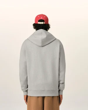 Person facing away from the camera, wearing a light gray hoodie and a red baseball cap, with brown pants visible at the bottom edge.