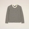 Black-and-white striped long-sleeve knit sweater with a crew neck, displayed against a beige background.