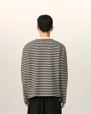 Back view of a person wearing a black-and-white striped shirt, standing against a pale wall.