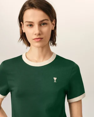 Close-up of a person wearing a green shirt with white collar trim and a small white heart on the chest.
