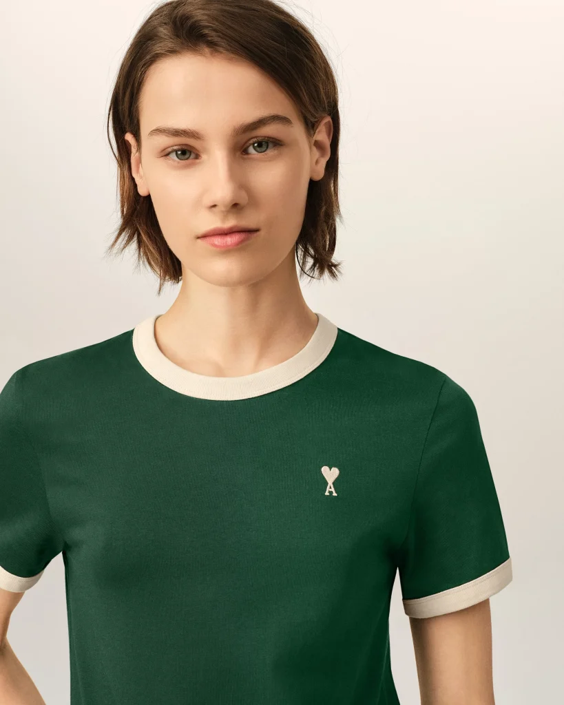 Close-up of a person wearing a green shirt with white collar trim and a small white heart on the chest.