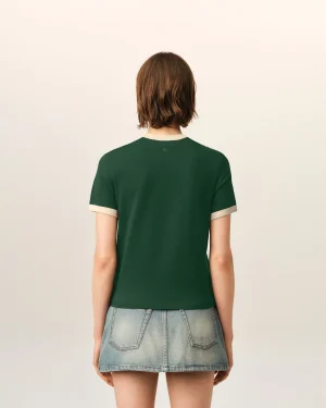 Back view of a person with short brown hair wearing a green T-shirt and a light denim skirt, standing against a pale background.
