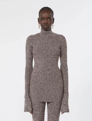 Model wearing a brown speckled knit turtleneck bodysuit with matching pants in a fitted silhouette and long sleeves with flared cuffs.