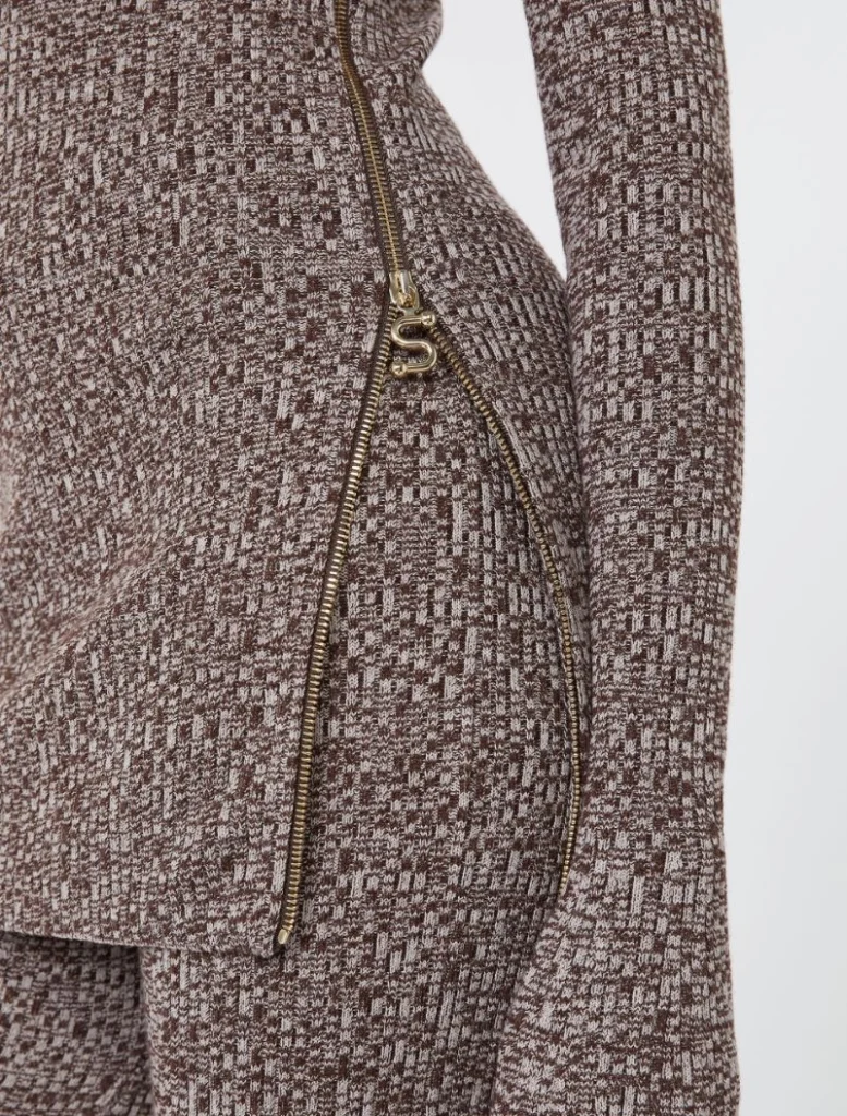 Close-up of a brown textured knit garment with a gold zipper and an S-shaped zipper pull.